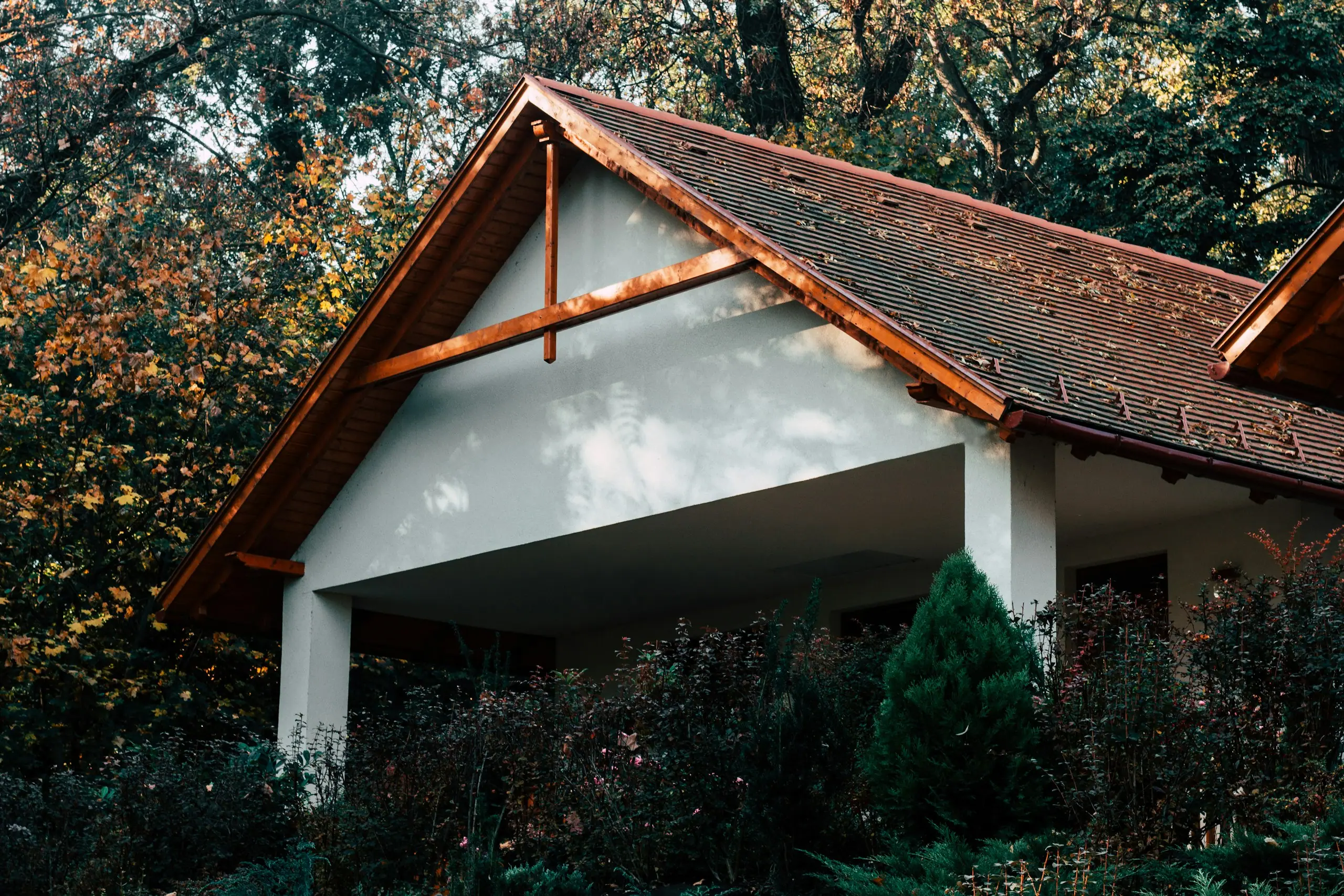 Einfamilienhaus mit Satteldach und Ziegeldeckung zwischen Bäumen im Herbst